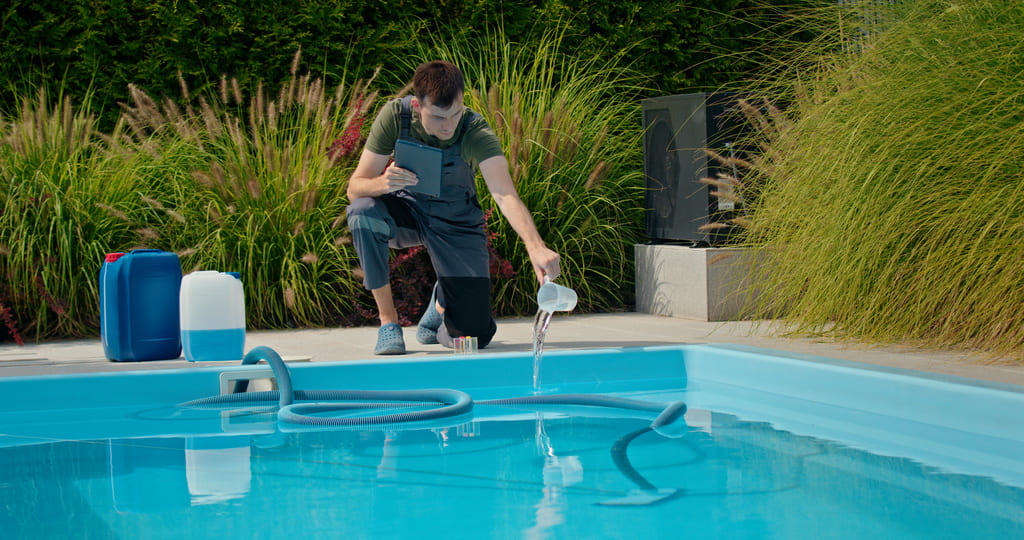 Technicien de l'entreprise versant un produit dans la piscine pour garantir son bon fonctionnement